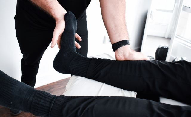 A physiotherapist demonstrating a calf stretch to a runner in a modern clinic, highlighting physiotherapy for running injuries like Achilles tendinitis.